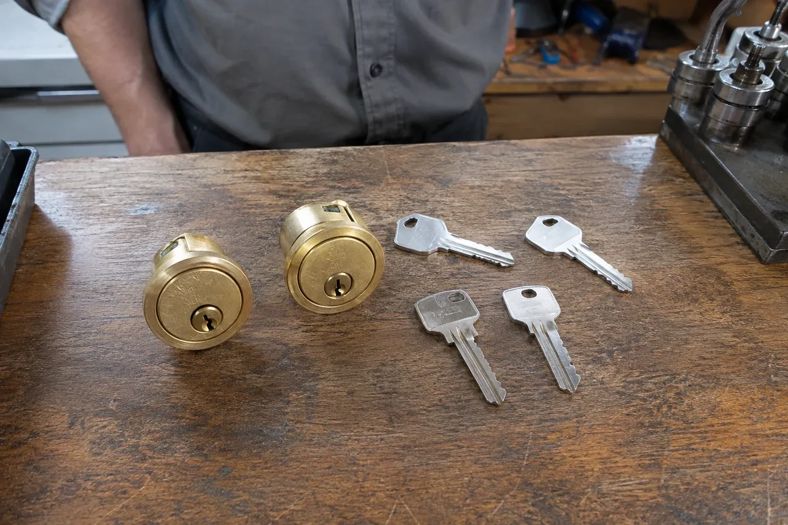 Two detached brass lock cylinders and four house keys on a wooden counter. — Lock Rekeying, East Gwillimbury